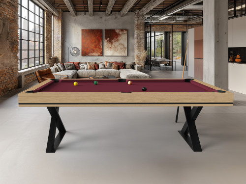 Billard Cross en chene nature liseret noir et tapis wine dans un loft en brique avec tableaux rouges et canape beige