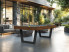 Harmony V Outdoor avec décor HPL teck, tapis bleu poudre et pieds gris ardoise, sur une terrasse design entourée de jardin