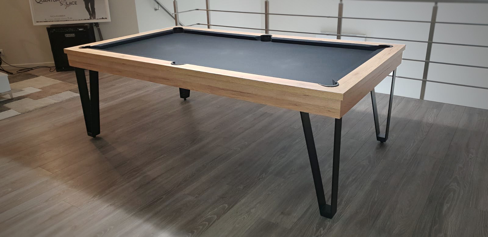 posé sur le parquet dans le salon de répétition à côté de l'ampli basse ce billard LIGHT en chêne éclairci veiné et aux pieds en métal noir tiré à quatre épingles invite à jouer un coup entre deux morceaux