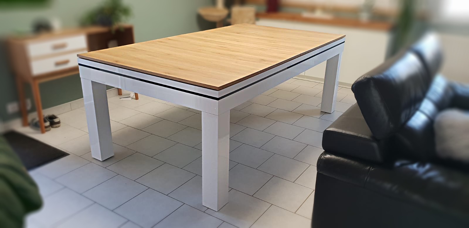 Novea blanc brillant sur carrelage blanc brillant avec plateau table en chêne veiné doré accordé au mobilier en bois du salon avec cuisine ouverte. Saisissez l'occasion de voir chez ce client un billard table à manger pas cher et rentable vus l'espace et la double utilité gagnés.