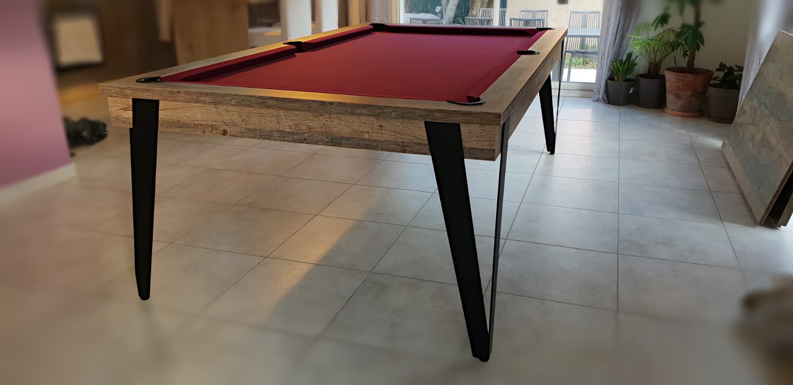 billard design aux fines lignes formées par les pieds en métal très fin qui portent un jeu couleur wine encadré de chêne vintage
