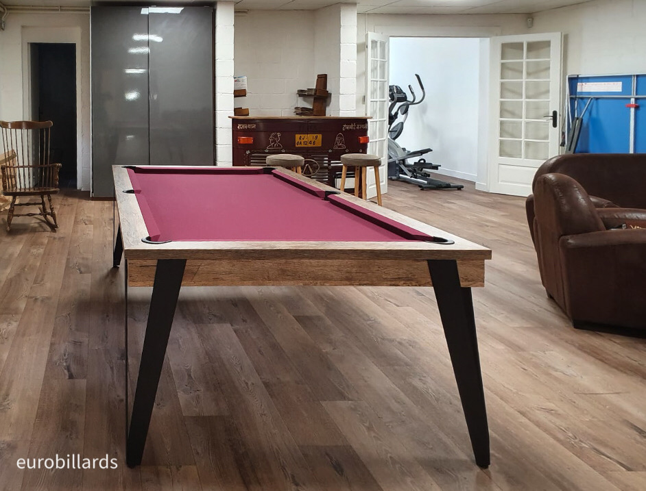 L'élégance du billard Pure dans sa finition chêne avec tissu bordeaux et ses pieds noirs métalisés vient poser un peu de rigueur sur la parquet au beau milieu du fourbi de cette salle de jeu et sport