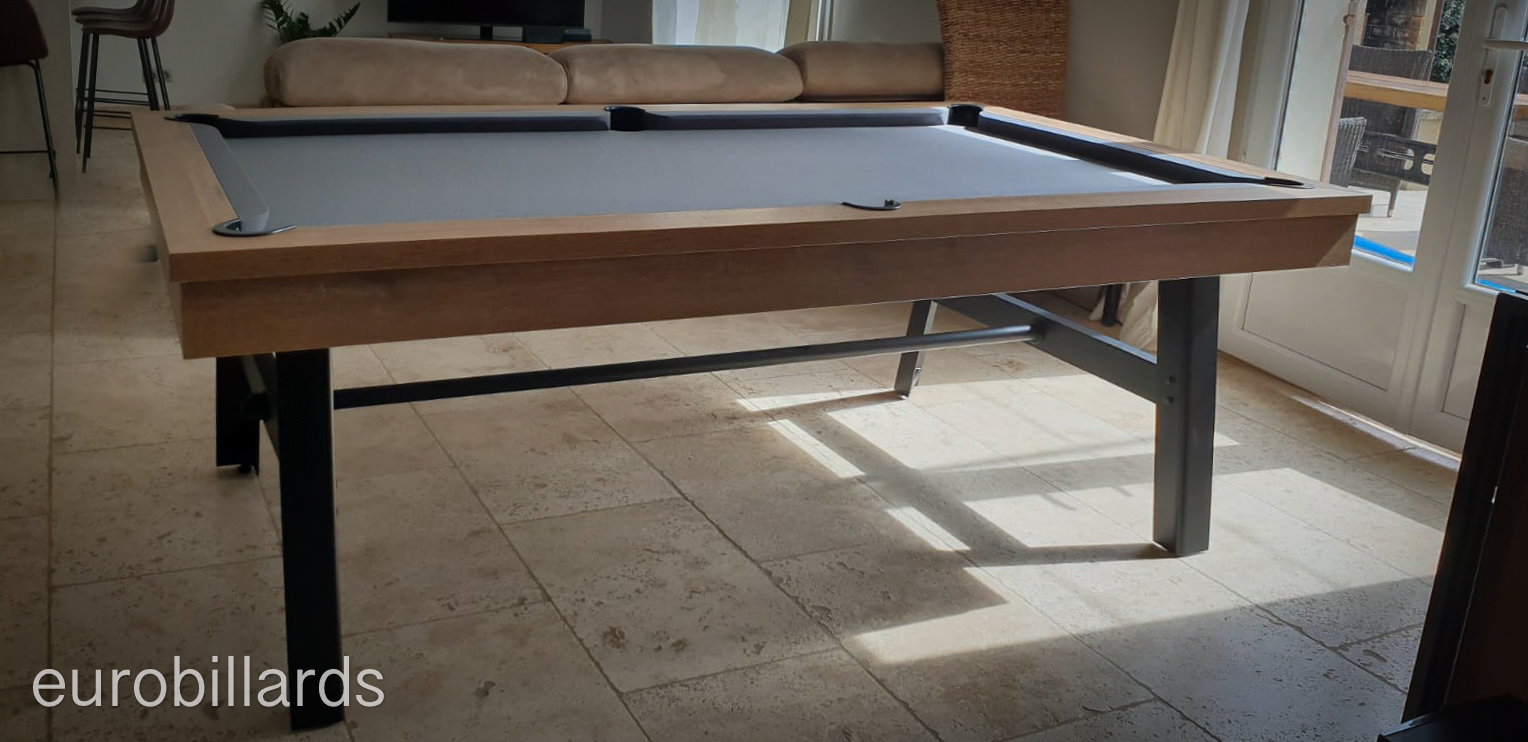 billard Vintage au tissu gris foncé finition CH Cognac et pieds noirs posé sur le sol en grès billard Vintage au tissu gris foncé finition CH Cognac et pieds noirs posé sur le sol en grès
