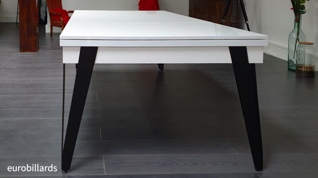 Billard transformable en table PURE de la marque Eurobillards avec son plateau ST finition nano blanc mat et des pieds en V de métal fin plié noir dans une salle de loisir eclectique où se mêlent fauteuil ancien, téléscope, jarre, plante et posées sur un parquet gris entouré de poutre teintée en rouge Billard transformable en table PURE de la marque Eurobillards avec son plateau ST finition nano blanc mat et des pieds en V de métal fin plié noir dans une salle de loisir eclectique où se mêlent fauteuil ancien, téléscope, jarre, plante et posées sur un parquet gris entouré de poutre teintée en rouge