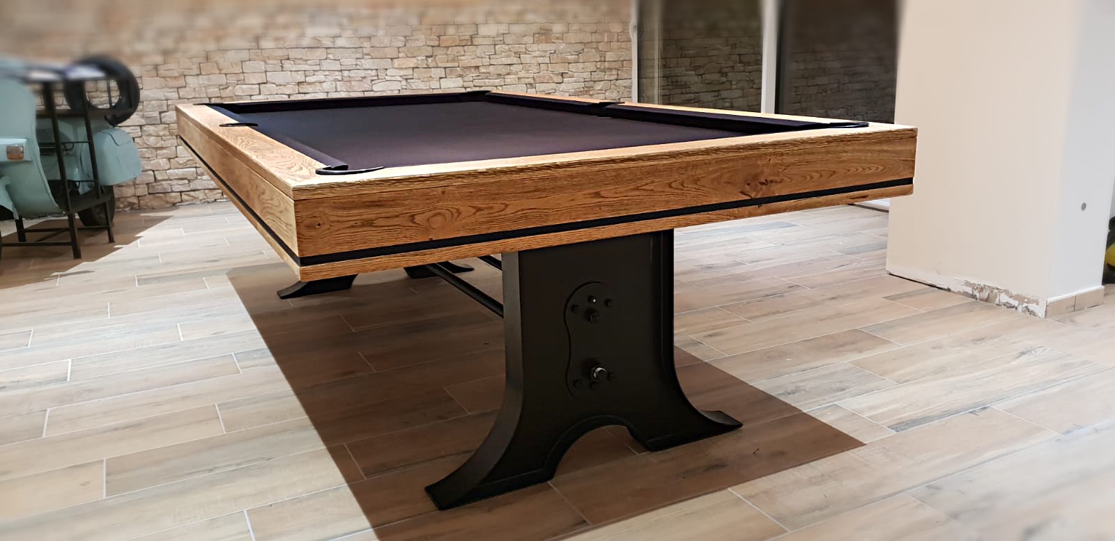 La finition bicolore du billard ATELIER avec son liseré et ses pieds noirs sur chêne brossé huilé renforce le style industriel de la table en laquelle il se transforme.