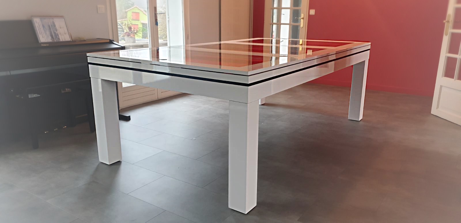 Cette magnifique table design brille de son blanc et également de son plateau de verre en trois parties qui laissent apparaitre le tapis de jeu orange du billard. Pour faire plaisir, il est facile d'achet un billard pas cher de marque en l'accordant à sa décoration.