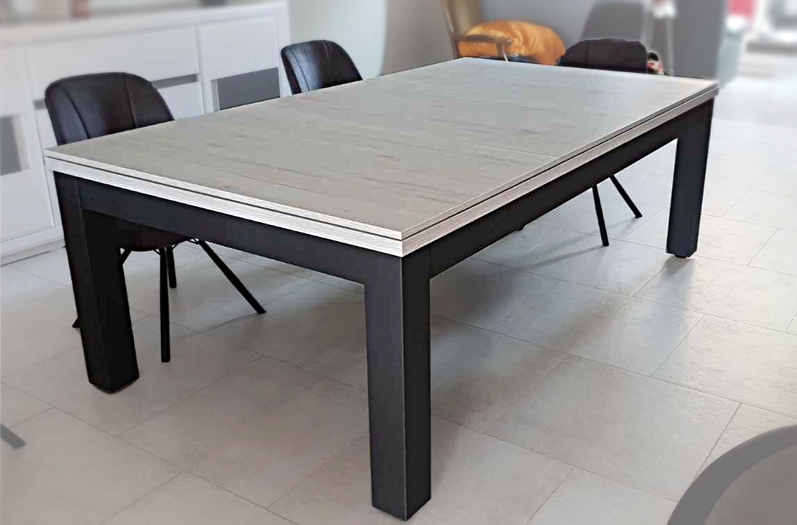 Le billard trendy en finition bicolore chêne blanchi veiné sur piétement noir nano anti-traces est transformé en une nouvelle table par la pose d'un plateau ST en trois parties dont la couleur évoque le carrelage en grès cérame de cet espace situé entre cuisine et salon où il rejoint le buffet blanc aux vitres noires